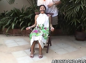 Asian teen tied almost and hand cuffed on a chair