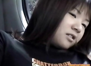 An Asian girl is sitting on the back seat of a car.  from http://alljapanese.net